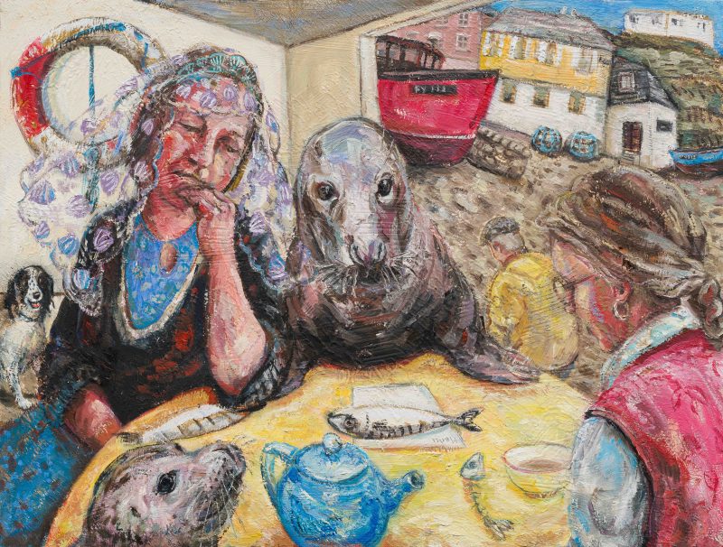 Two women and two seals sit at a table having tea and mackerel snacks beside the harbour.